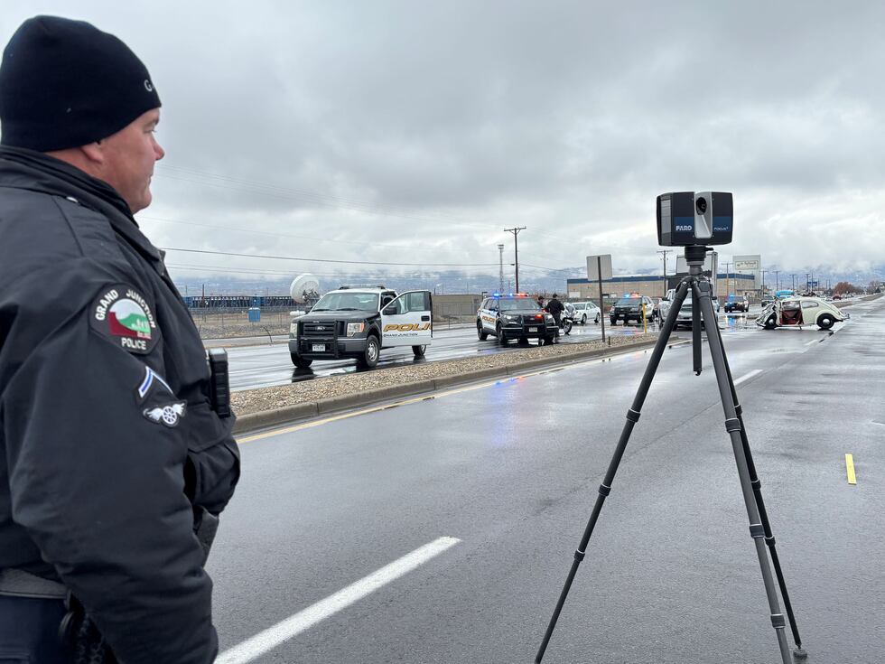 A Grand Junction Police Officer stands next to a Faro Focus laser scanner some distance away...